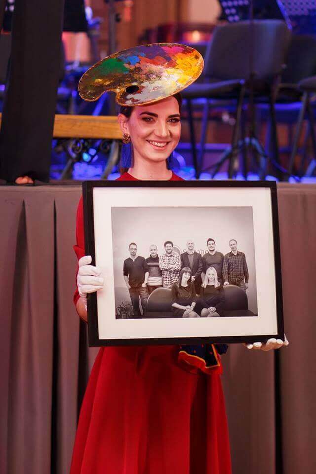 Symphonian wearing an artsy hat and holding a framed picture